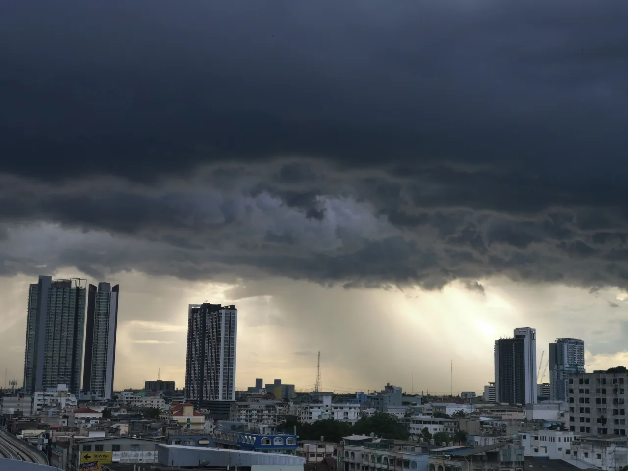 Tall buildings under storm with sun breaking through